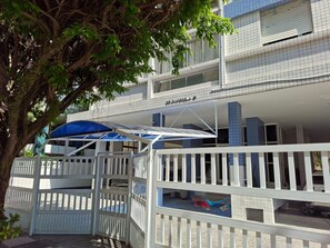 A hotel with a gated entrance, a covered outdoor area, and a building with blue-tiled balconies.