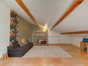 A cozy loft bedroom with a dark sofa, a decorative mirror, and a patterned rug. - Bail mobilité - Villa avec 4 ch, piscine & vue (La Penne-sur-Huveaune)