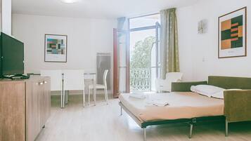 Une chambre d’hôtel équipée d’un lit, d’un bureau, d’une chaise, d’une télévision et décorée avec des œuvres d’art aux murs.