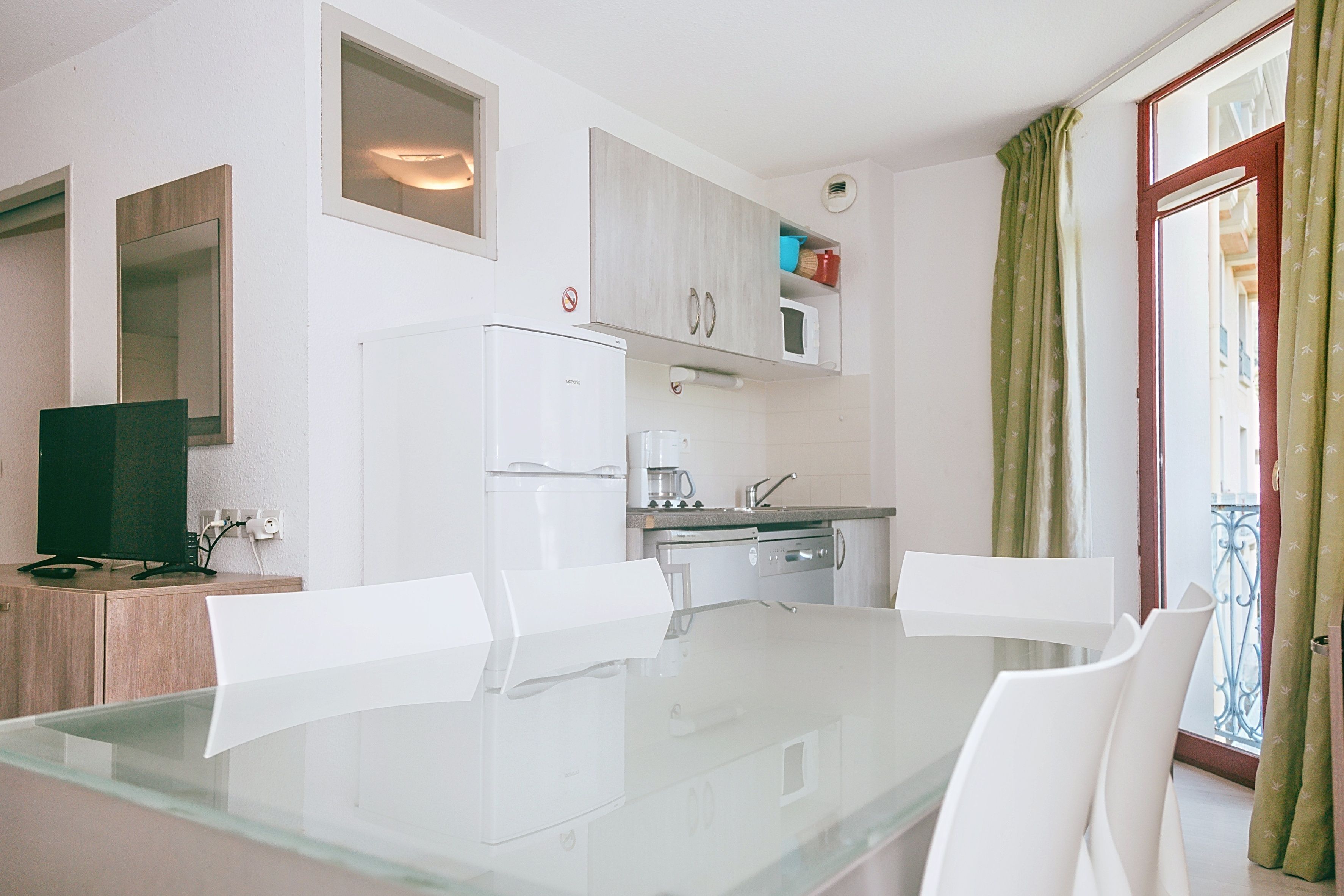 Cocina compacta con mesa, sillas, refrigerador, microondas y cafetera.