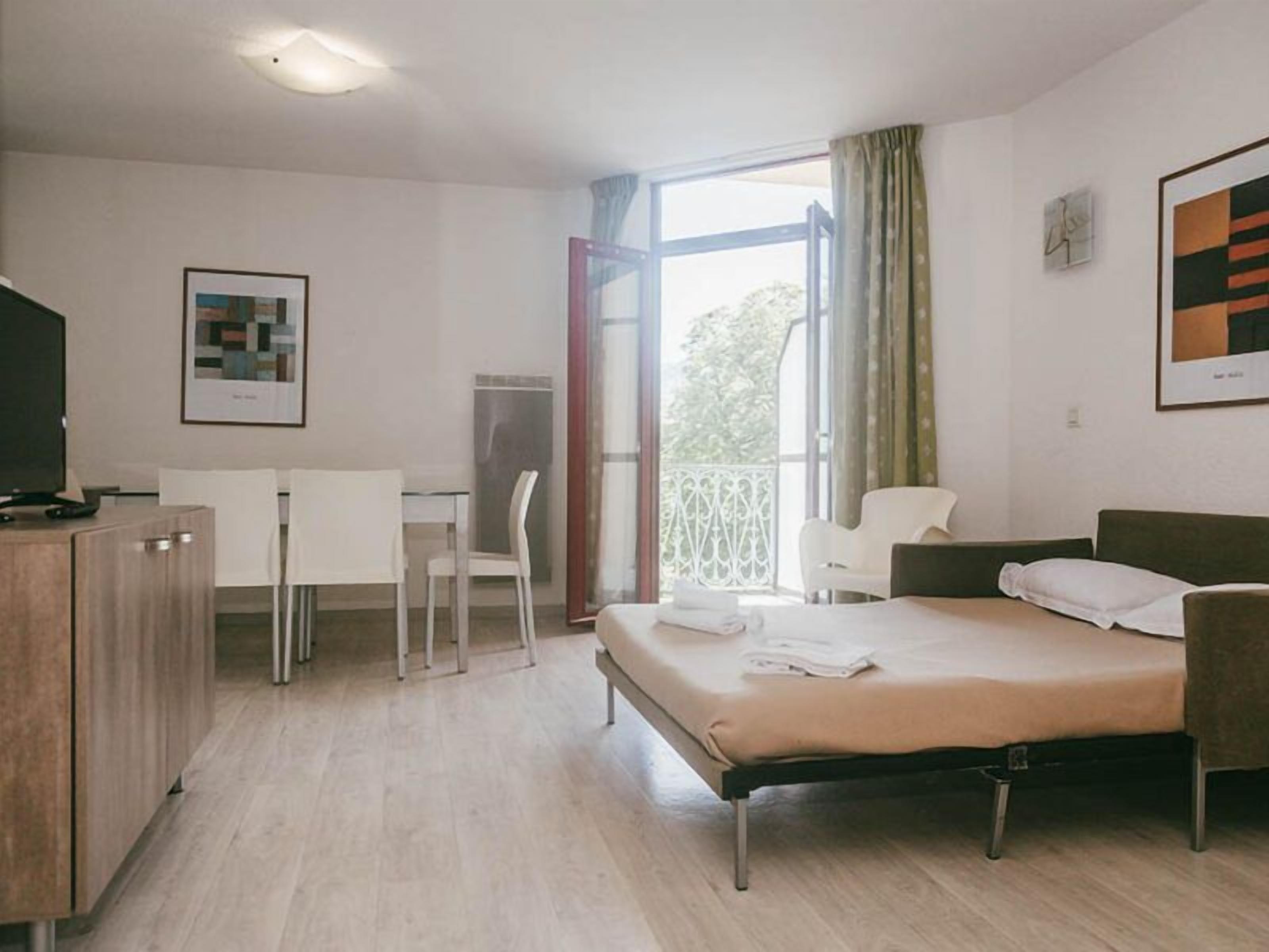 Une chambre d’hôtel avec un lit, un bureau, une chaise et un téléviseur.