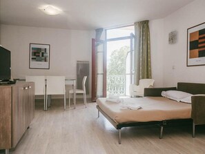 Une chambre d’hôtel avec un lit, un bureau, une chaise et un téléviseur.