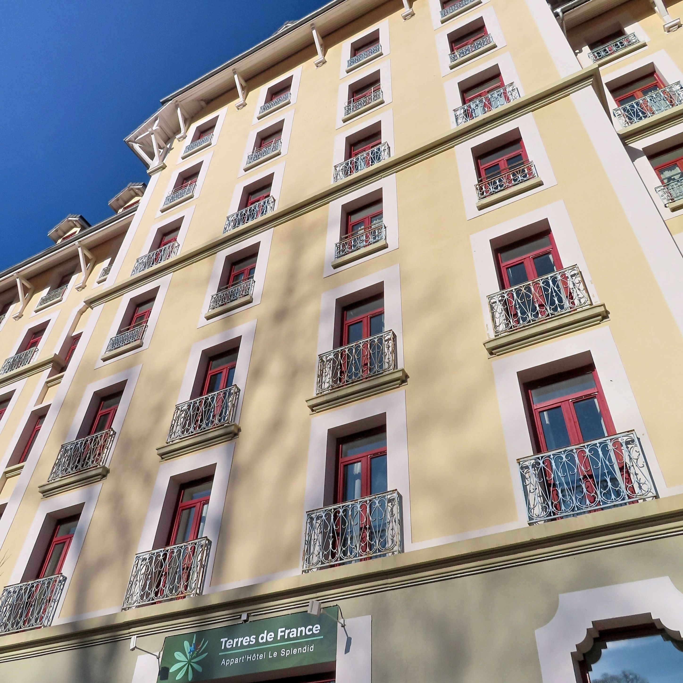 Um hotel com vários andares, varandas e uma placa com 'Terres de France'.