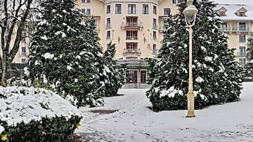 Un sentier enneigé mène à un bâtiment doté de nombreux balcons et d’une entrée centrale.
