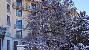 Ein mehrstöckiges Gebäude mit Balkonen und einem schneegebundenen Baum davor.