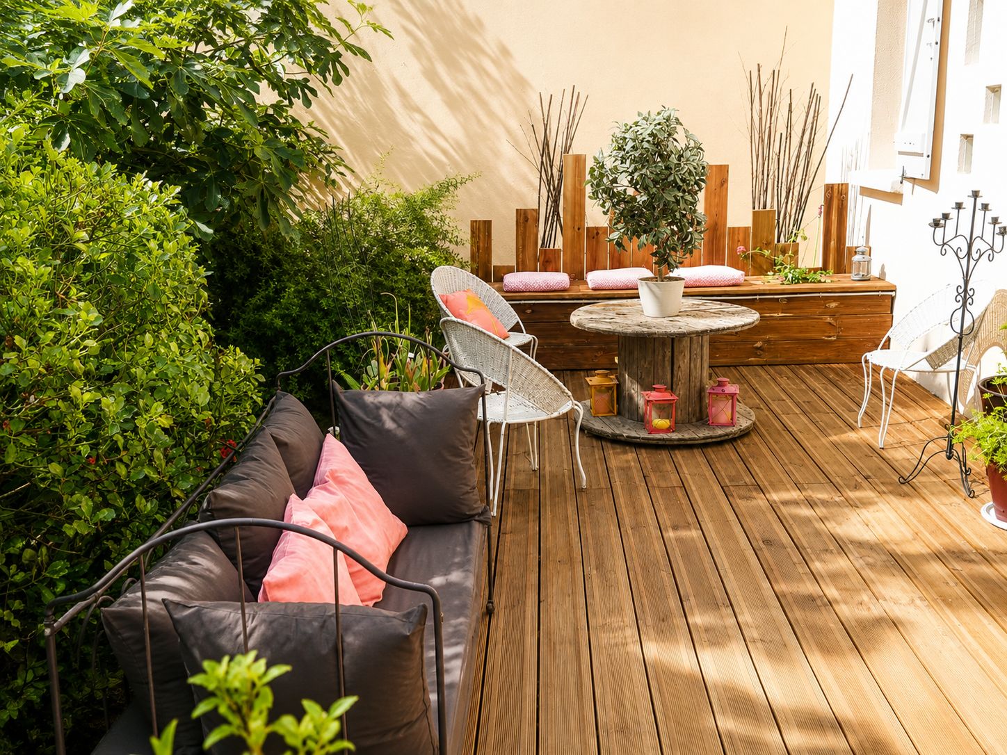 A wooden deck with a round table, a sofa with cushions, and a chair.