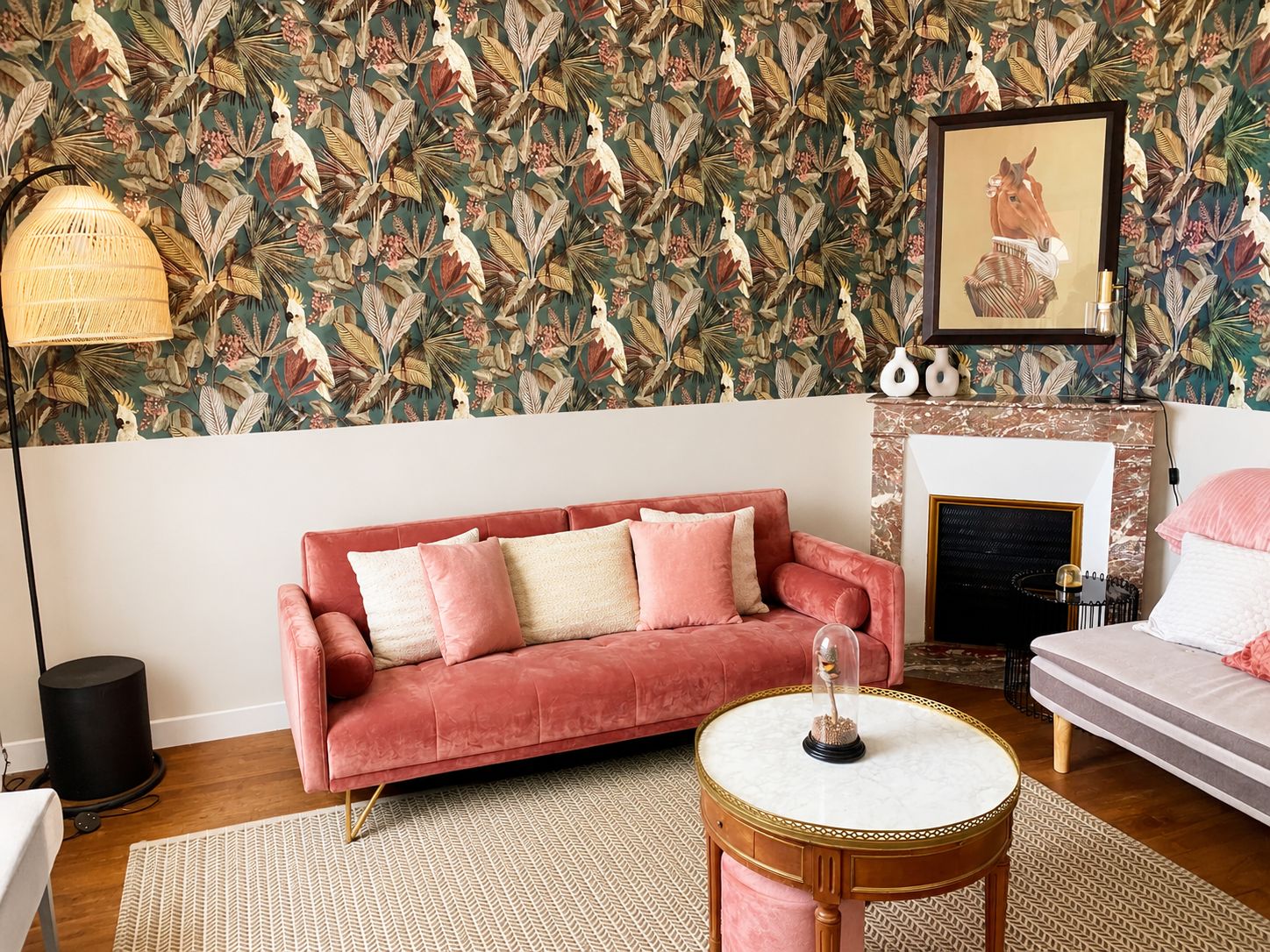 A living room with a patterned wallpaper, a pink sofa, a round coffee table, and a fireplace.