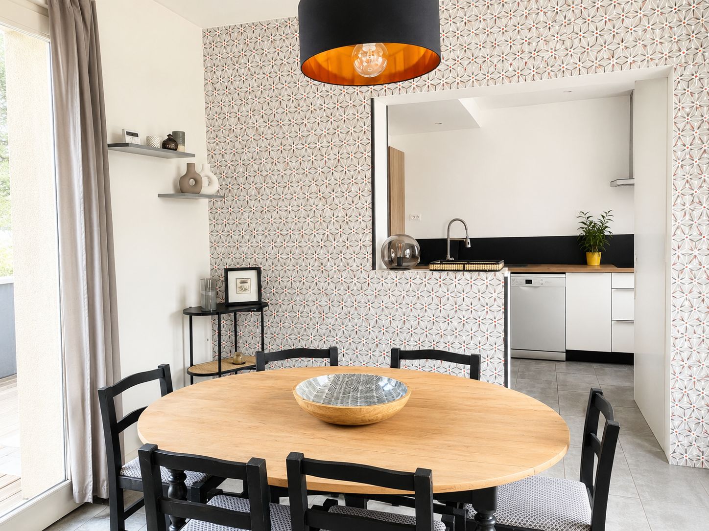 Un espace repas moderne avec une table ronde en bois, des chaises noires et un grand vase décoratif placé au centre.
