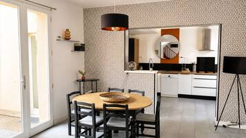 Una cucina moderna con zona pranzo, che include un tavolo rotondo, sedie, una lampada a sospensione e un forno integrato.