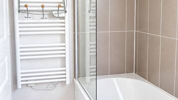 A bathroom with a white bathtub, a glass shower enclosure, and a white towel rack with wooden knobs.