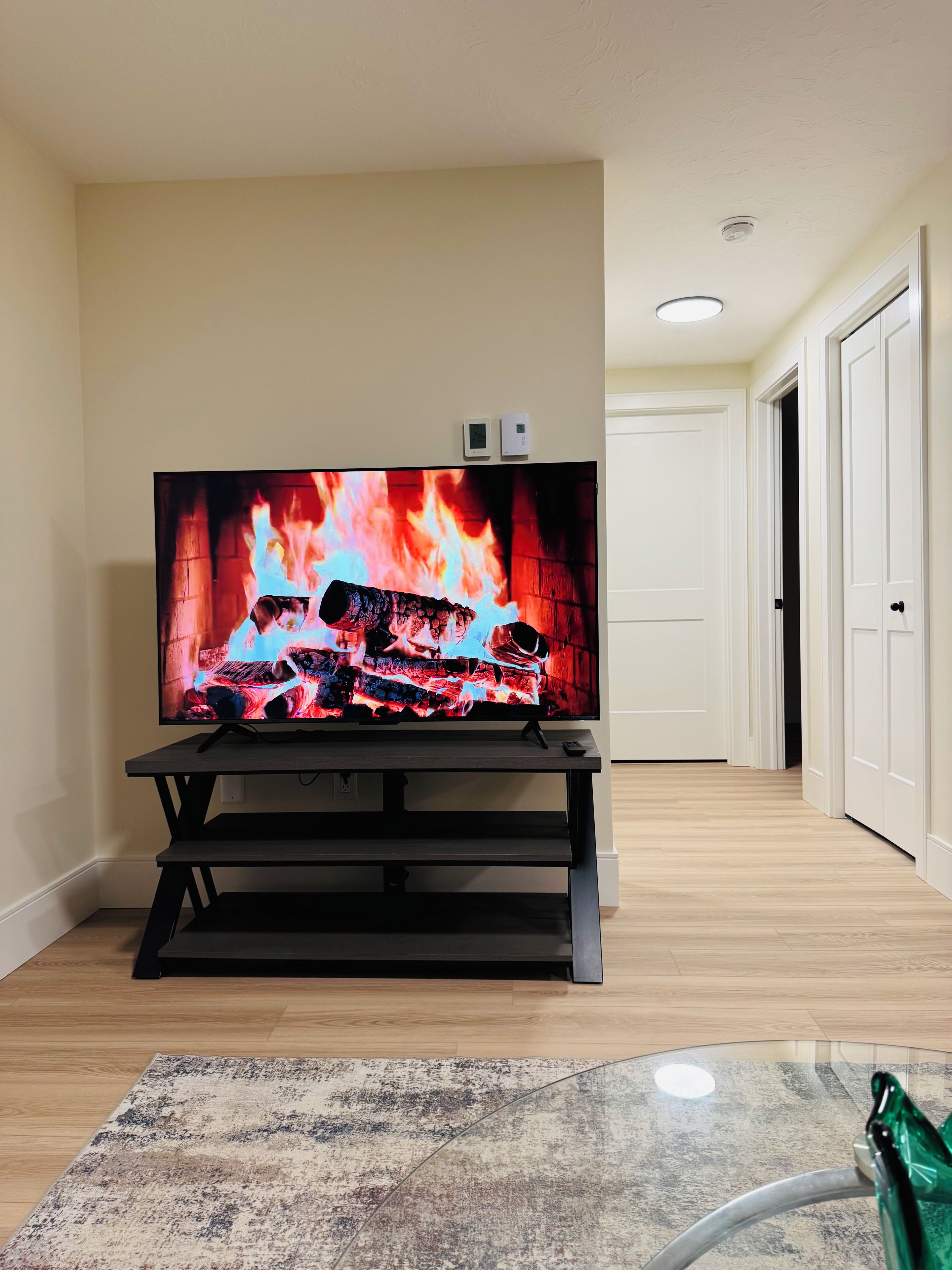 A flat-screen TV on a stand in a room with a wooden floor and a patterned rug.