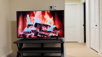 A flat-screen TV on a stand in a room with a wooden floor and a patterned rug.