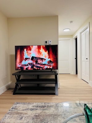 A flat-screen TV on a stand in a room with a wooden floor and a patterned rug.