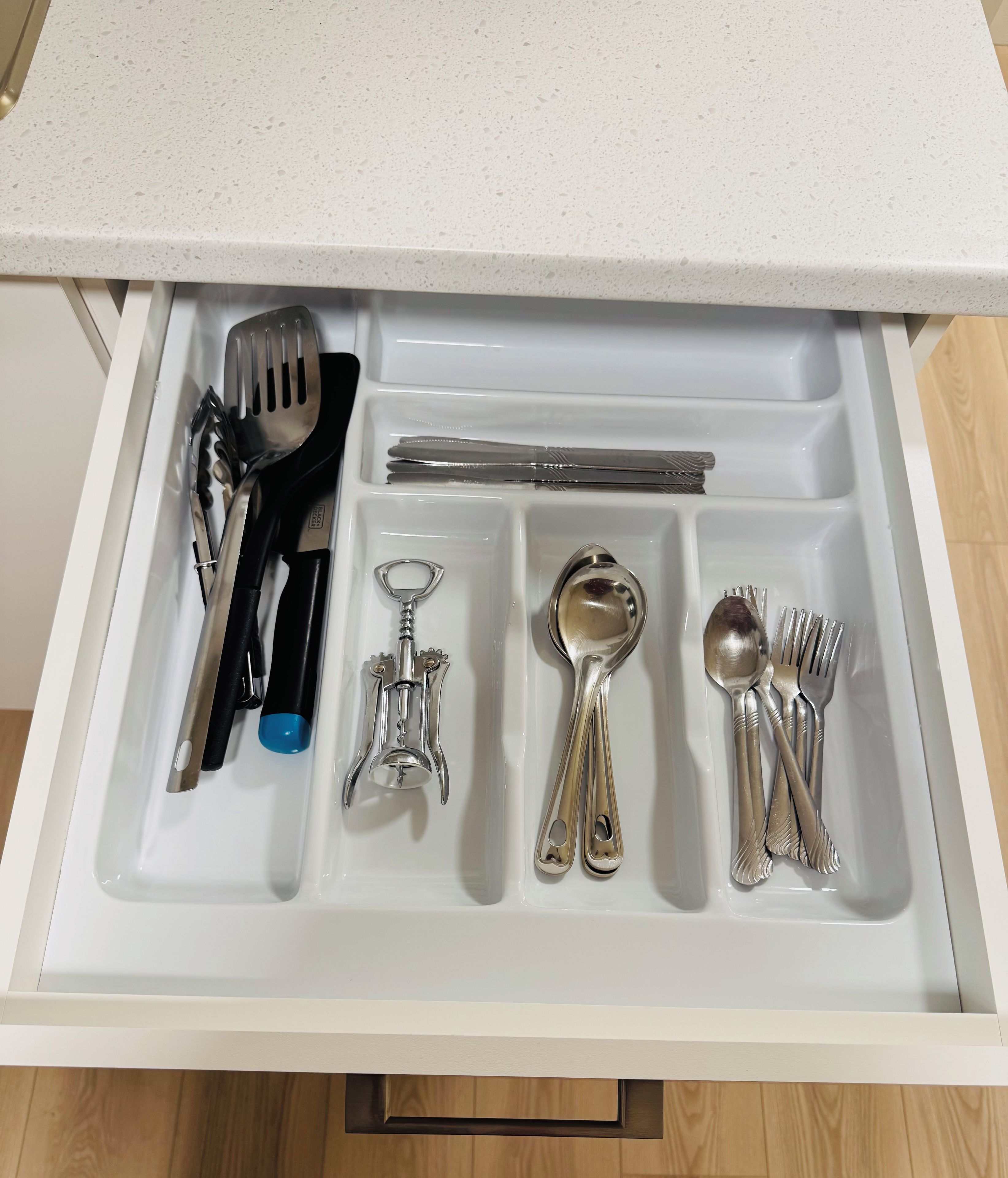 A drawer containing various kitchen utensils including a spatula, knife, spoon, and forks.
