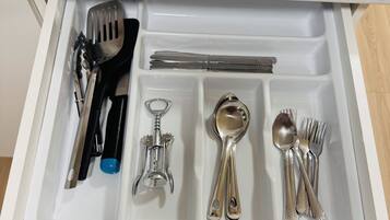 A drawer containing various kitchen utensils including a spatula, knife, spoon, and forks.
