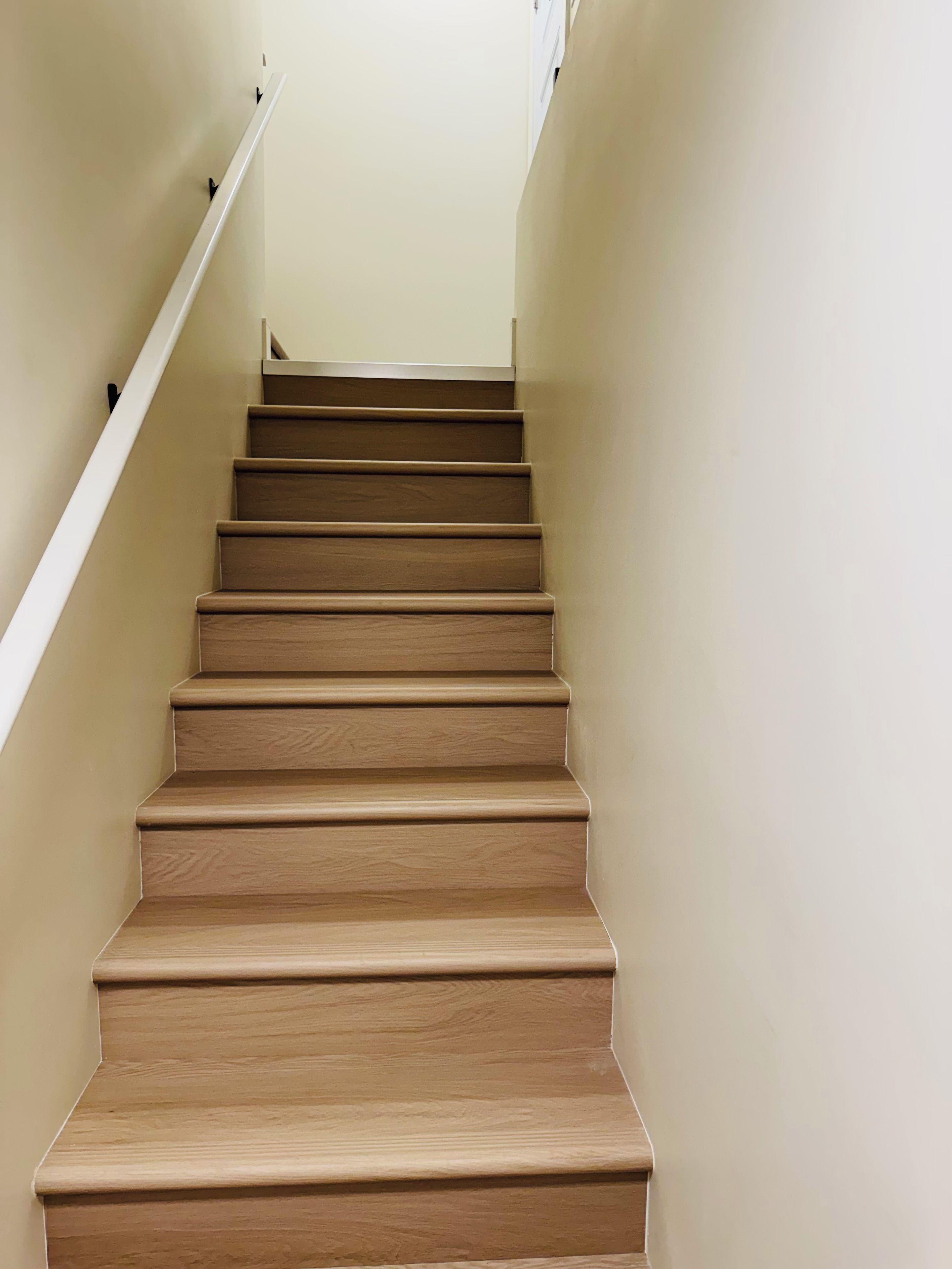 A staircase with wooden steps and white handrails, leading upwards.