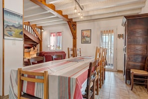 A dining area with a long table, chairs, and a staircase leading to an upper level.