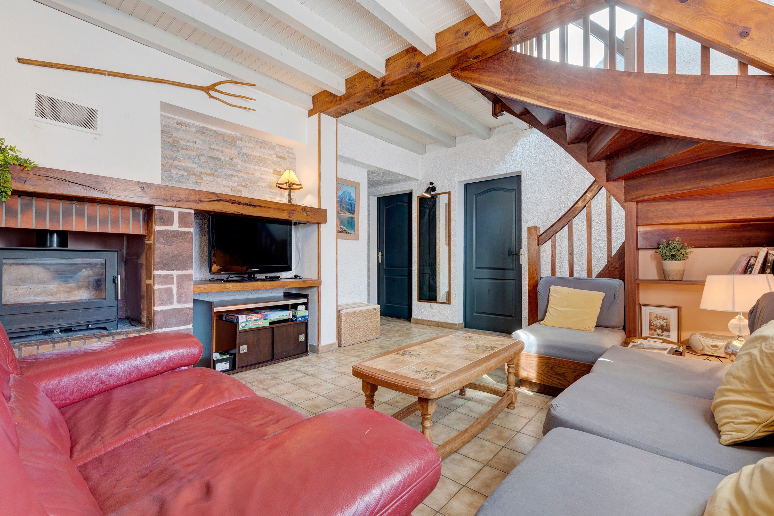 Una sala de estar acogedora con chimenea, sofá de cuero y vigas de madera.