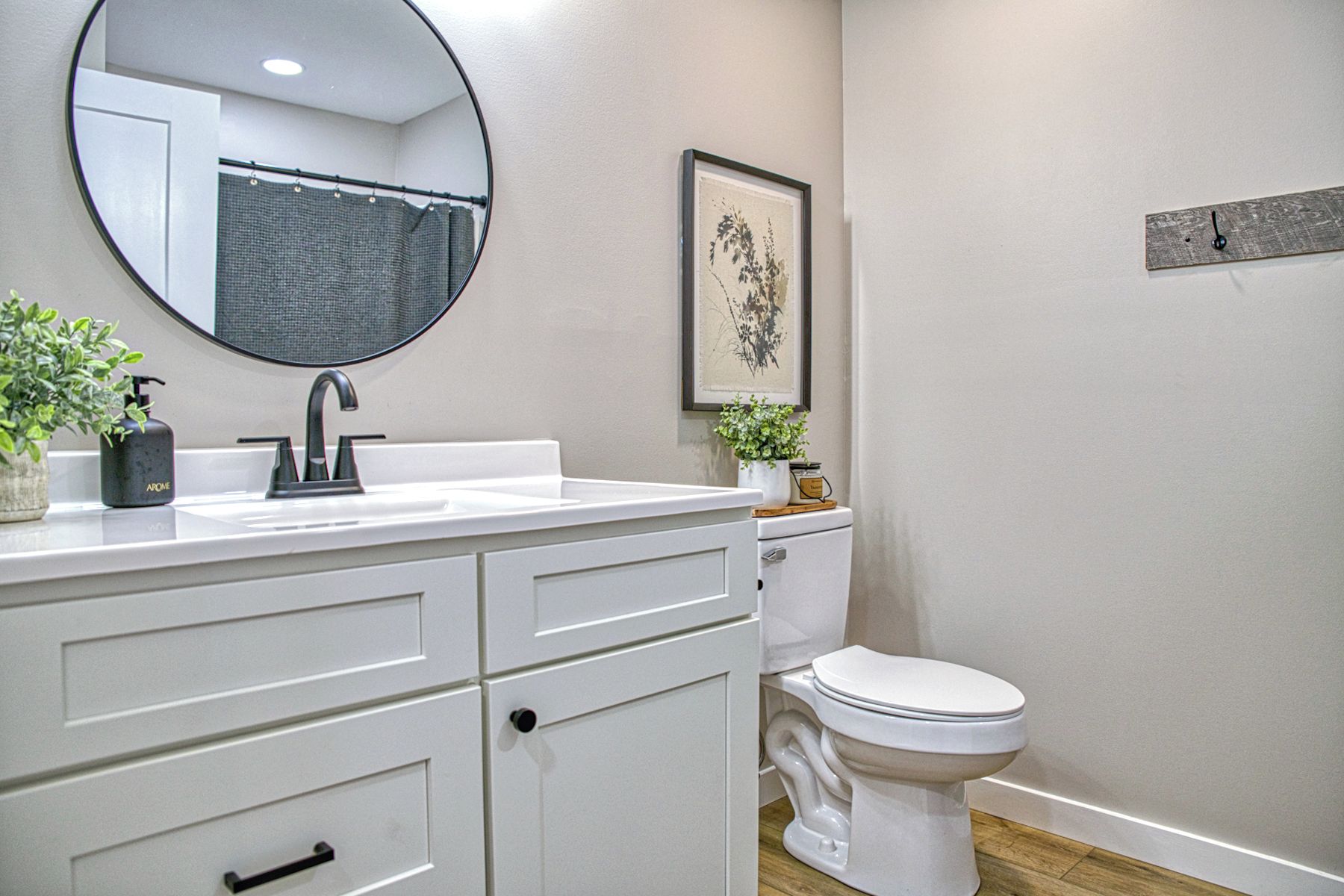 Un bagno con un lavandino bianco, uno specchio, un WC e un quadro appeso al muro.