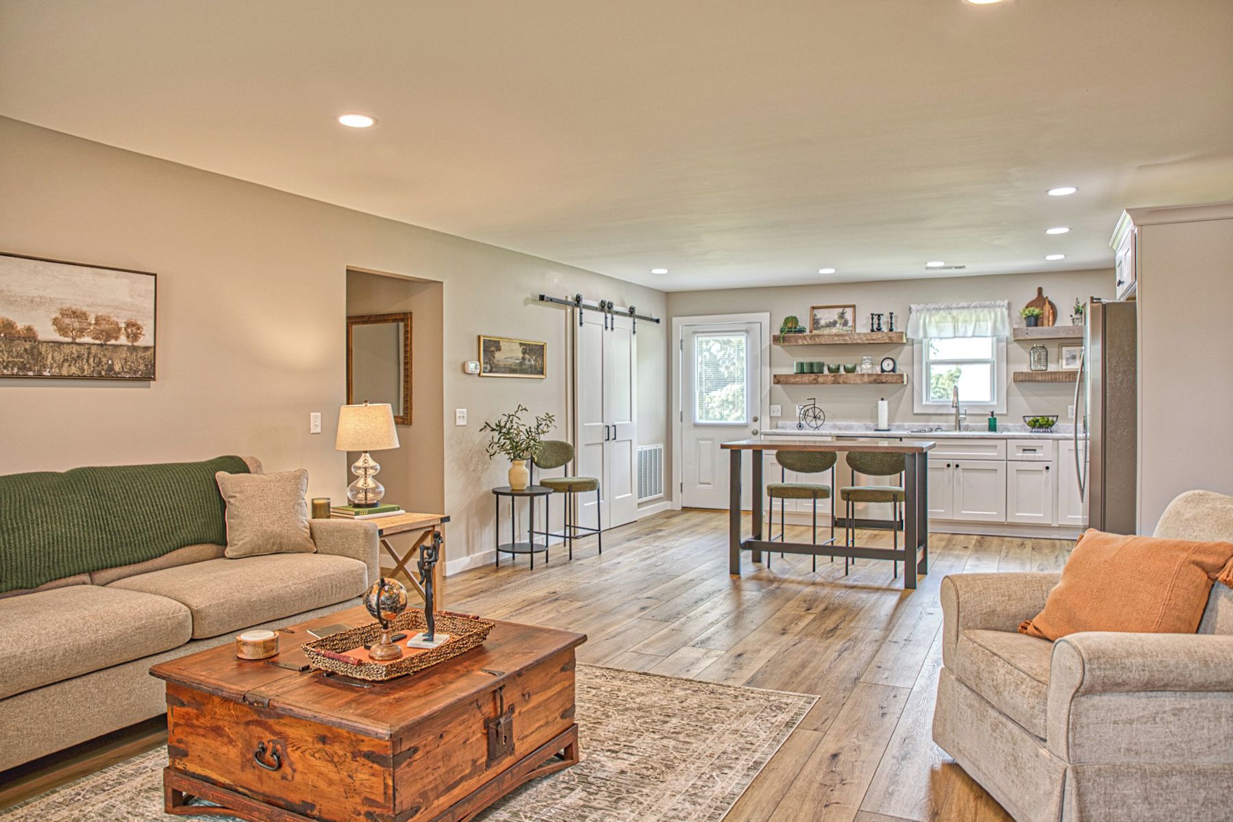 A spacious living room with a wooden coffee table, a sofa, and a dining area with a kitchen in the background.