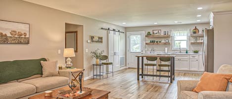 A spacious living room with a wooden coffee table, a sofa, and a dining area with a kitchen in the background.