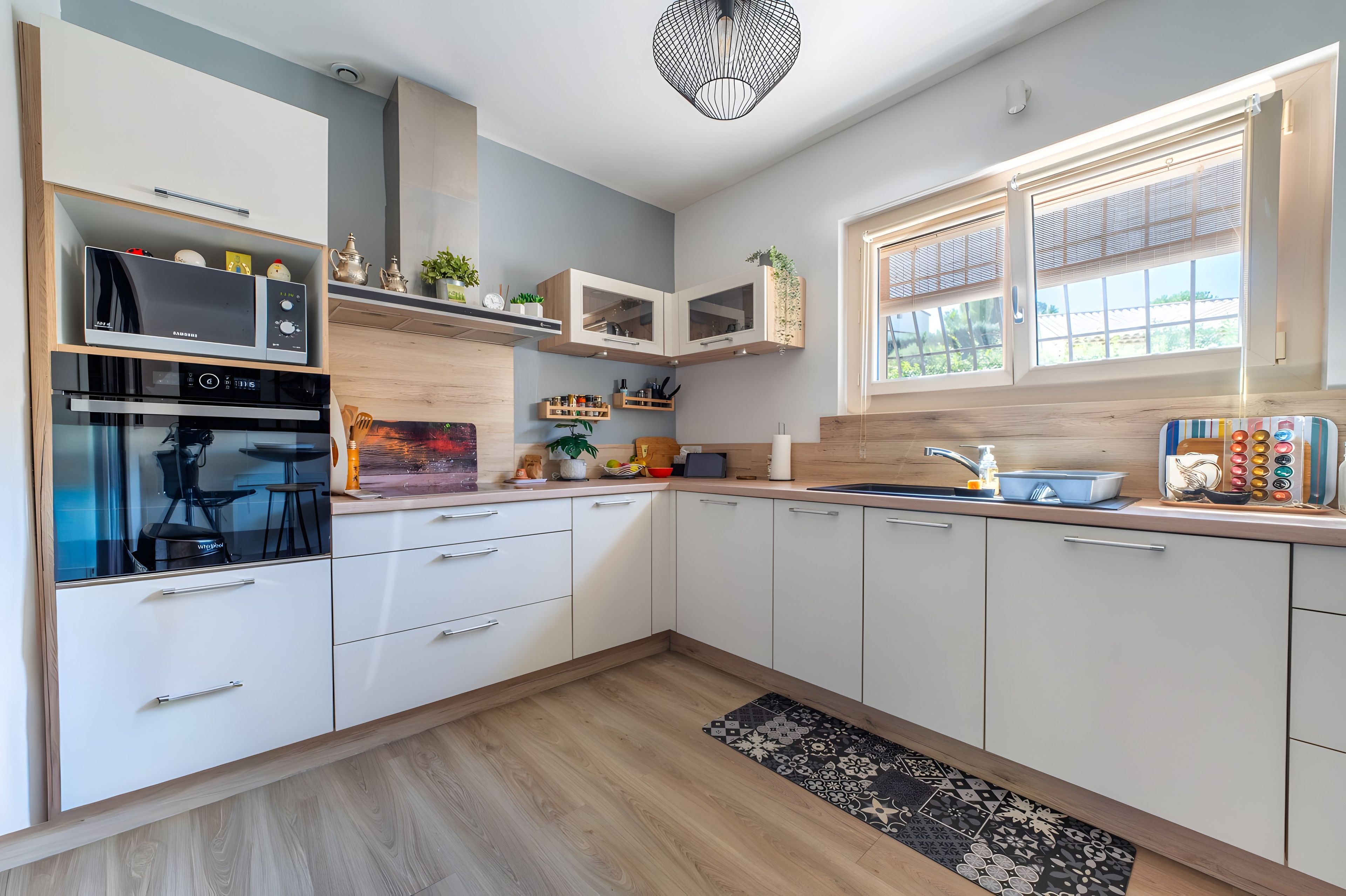 A modern kitchen with built-in appliances, wooden cabinets, and a window with blinds.