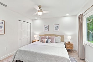 A bedroom with a bed, bedside tables, a ceiling fan, and framed artwork on the wall. - Upscale Bonita Springs  Pool, Spa & Privacy (Bonita Springs)