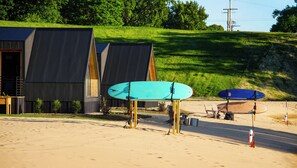 A building with a sloped roof and a sandy area with surfboards. - The Luna Cottage at Sandblox Resort (Benton Harbor)