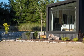 A modern building with a large window, surrounded by a natural landscape with trees and a body of water. - The Luna Cottage at Sandblox Resort (Benton Harbor)
