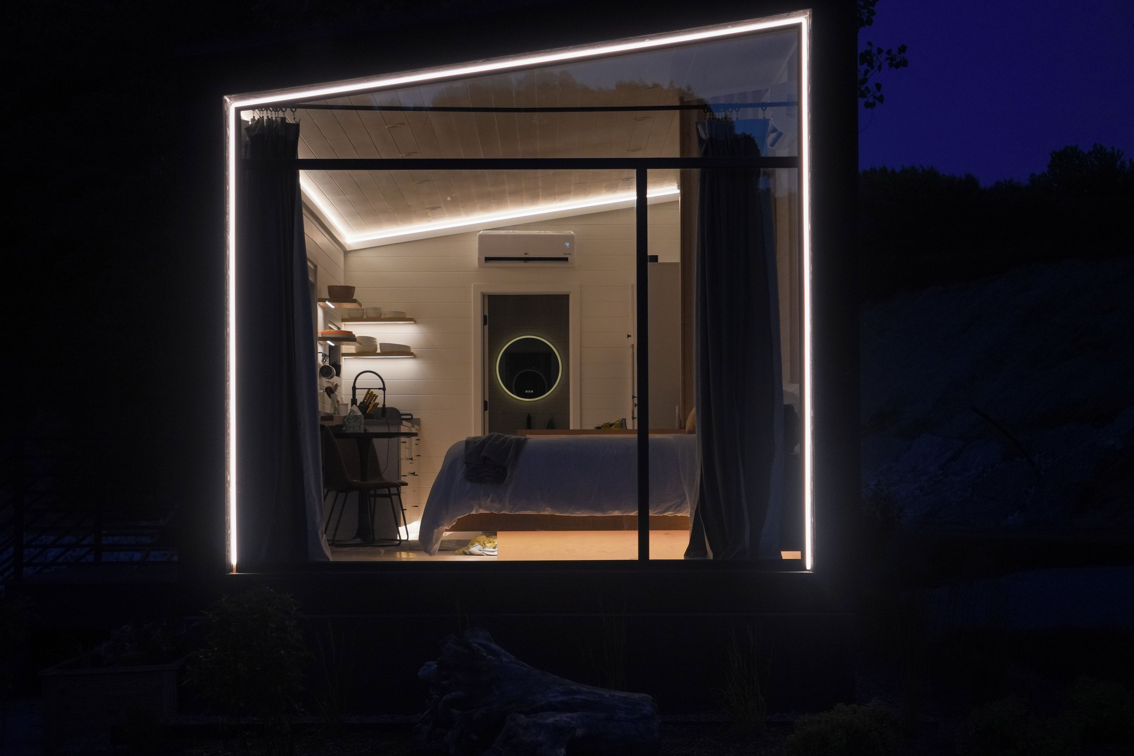 A modern, well-lit room with a bed, a desk, and a circular light fixture.