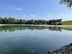 A calm lake with a reflection of the sky and surrounding trees. There are several buildings with dark roofs along the shore. - The Luna Cottage at Sandblox Resort (Benton Harbor)
