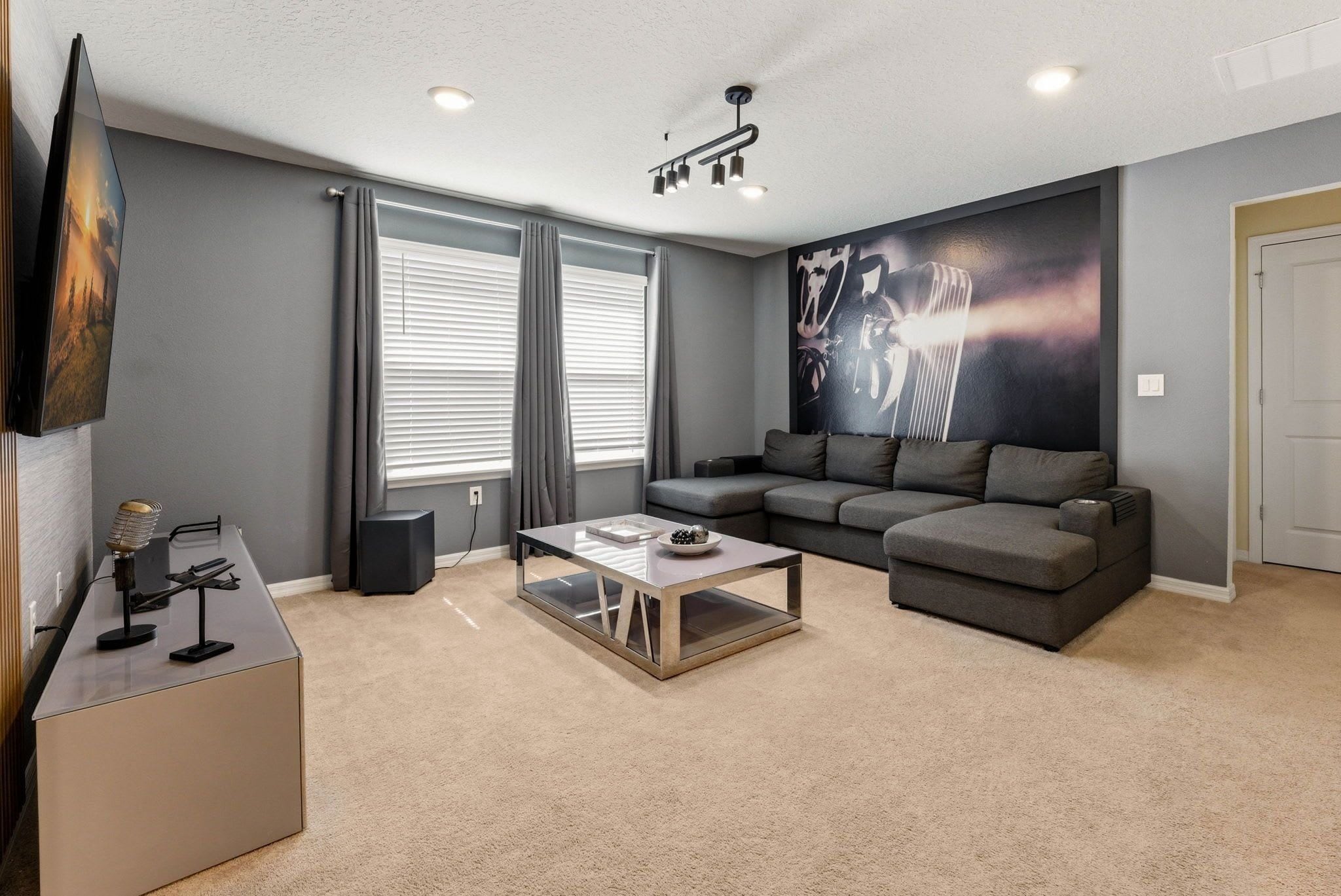 A modern living room with a flat-screen TV, a sofa, a coffee table, and a large wall mural.