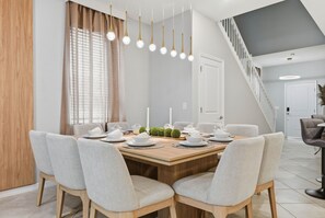 Een eetruimte met een houten tafel, gedekt voor vier personen, omringd door gestoffeerde stoelen.