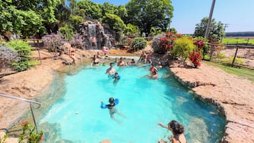 A swimming pool with clear water, surrounded by rocks and greenery.