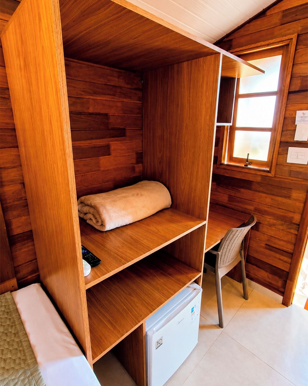 Una habitación pequeña con una litera de madera, un escritorio y una silla.