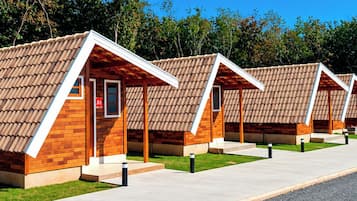 A row of modern, single-story cabins with pitched roofs, wooden exteriors, and a paved walkway in front.