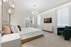 Un dormitorio moderno con una cama grande, un tocador, un espejo y un televisor.