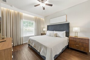 A hotel room with a bed, bedside tables, a ceiling fan, and a window with curtains. - West Lucaya 4BR Home Near Disney & Parks (Kissimmee)