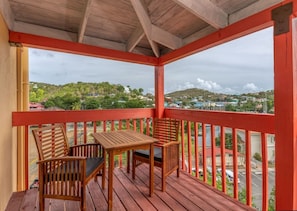 Eine Holzterrasse mit roter Geländer, zwei Holzstühlen und einem Tisch.