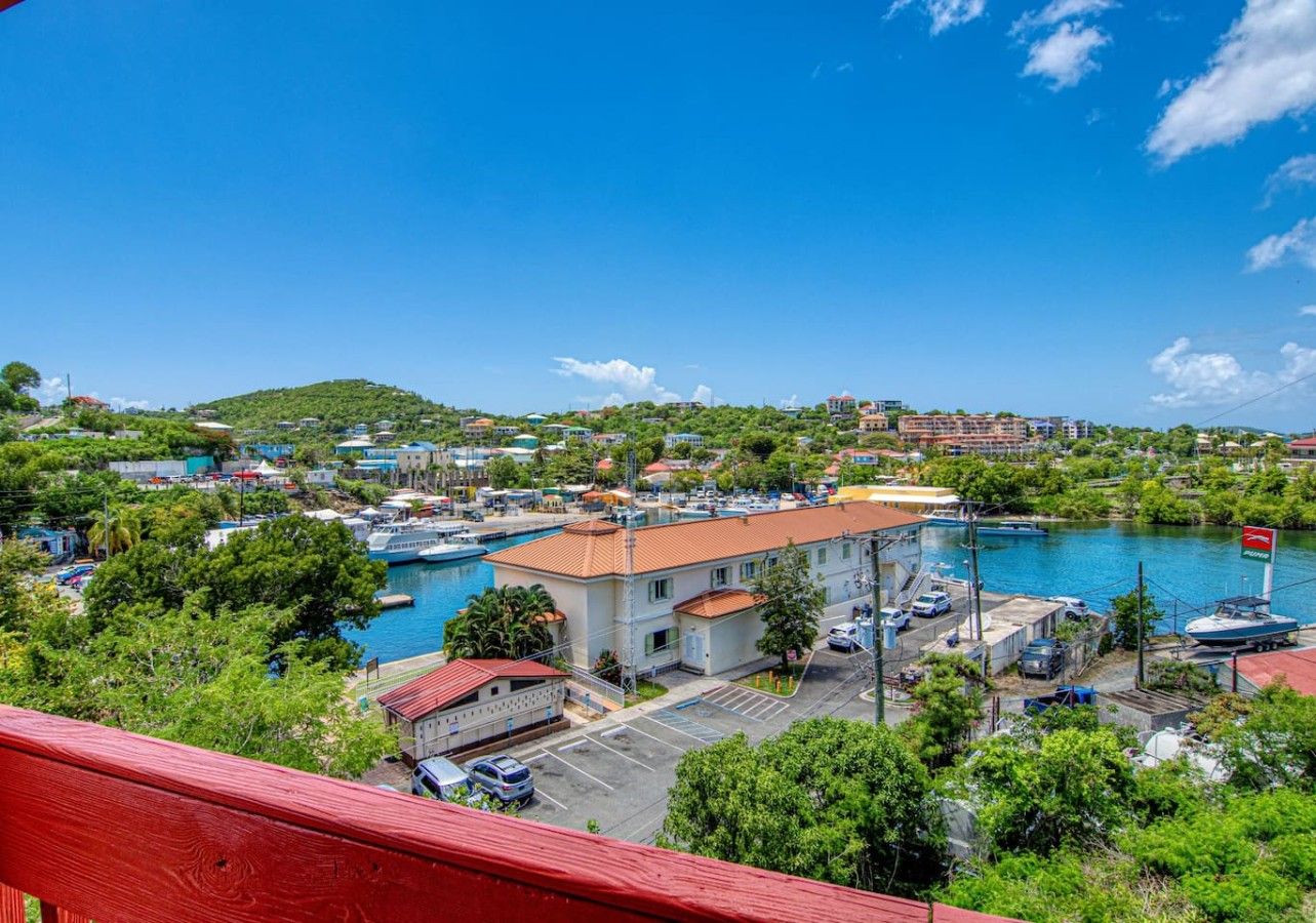 A coastal town with a marina, buildings, and a hill in the background.