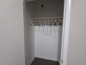 Ein Kleiderschrank mit einer Holzstange und mehreren Kleiderbügeln.