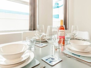 A dining table set with white plates, bowls, wine glasses, and a bottle of HIBRIDGE wine. - Private Beach-Front Apartment on the English Riviera with outdoor courtyard (Paignton)