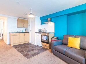 A compact living space with a kitchenette, a sofa, and a dining area. - Private Beach-Front Apartment on the English Riviera with outdoor courtyard (Paignton)