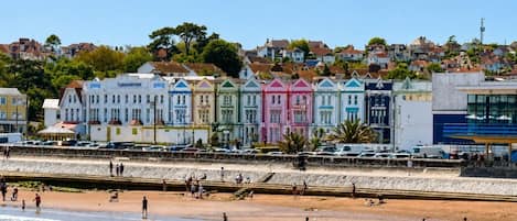 A beachfront hotel with colorful buildings, a sandy beach, and a clear sky.