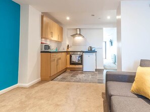 A modern kitchen with wooden cabinets, a microwave, and a dishwasher. - Private Beach-Front Apartment on the English Riviera with outdoor courtyard (Paignton)