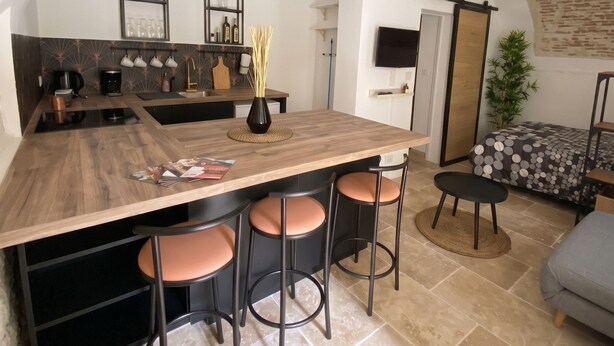Una cocina moderna con una isla central, taburetes de bar y una zona de comedor con sofá y mesa.