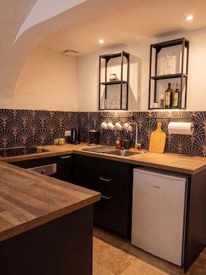 Una cocina moderna con armarios oscuros, encimera de madera y lavavajillas integrado.