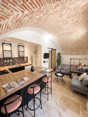 Una cocina moderna con una isla central, taburetes de bar y una mesa de comedor.