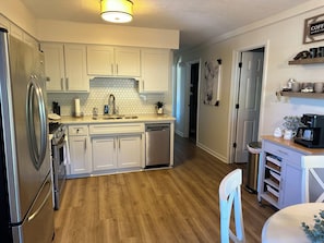 A modern kitchen with white cabinets, a stainless steel refrigerator, a dishwasher, and a coffee maker on the counter. - Robin’s Nest Peaceful Kentucky Country Escape (La Grange)