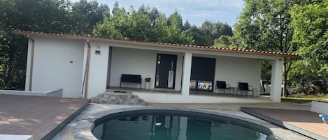 A modern house with a swimming pool, a covered patio, and a car parked outside.